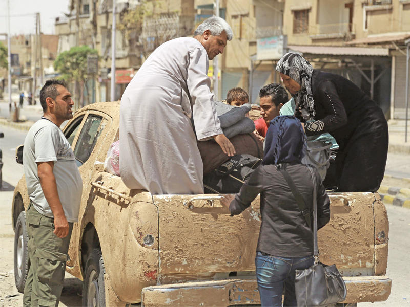 عائلة سورية تترك الحسكة بعد تصاعد القتال فيها أمس الأول  (أ ف ب)