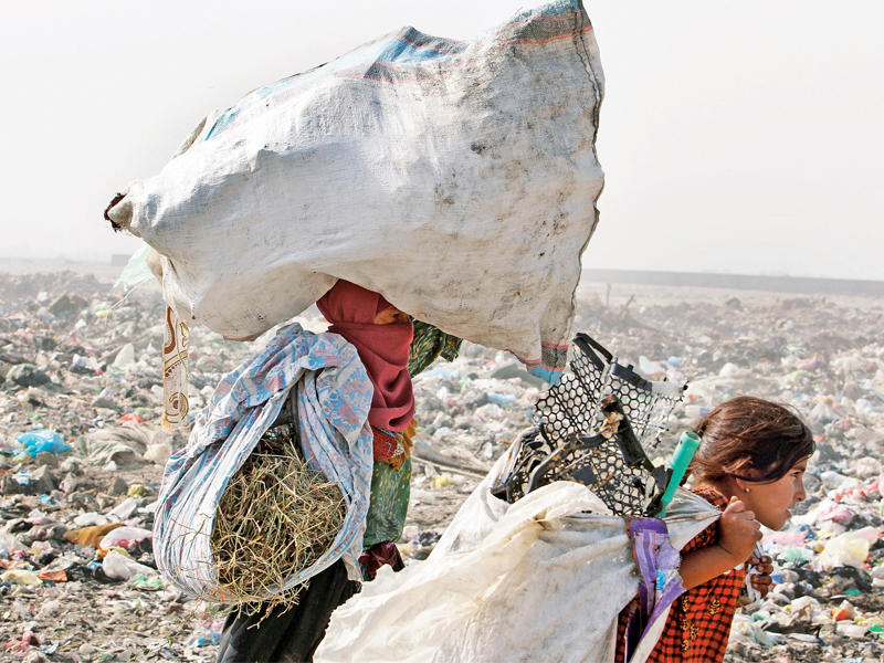 عراقية وابنتها تجمعان القمامة في ضواحي بغداد أمس (رويترز)