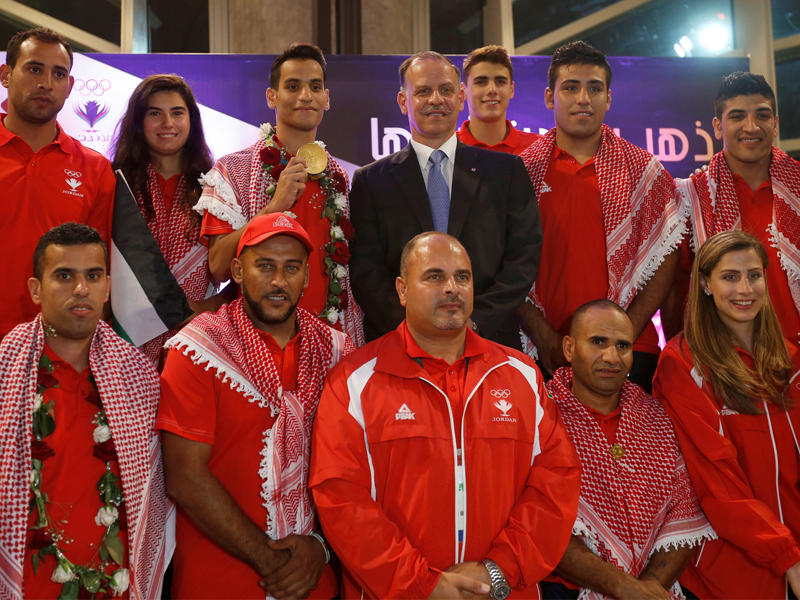 أبوغوش رافعاً ميداليته الذهبية متوسطاً فريق البعثة الأردنية الأولمبية