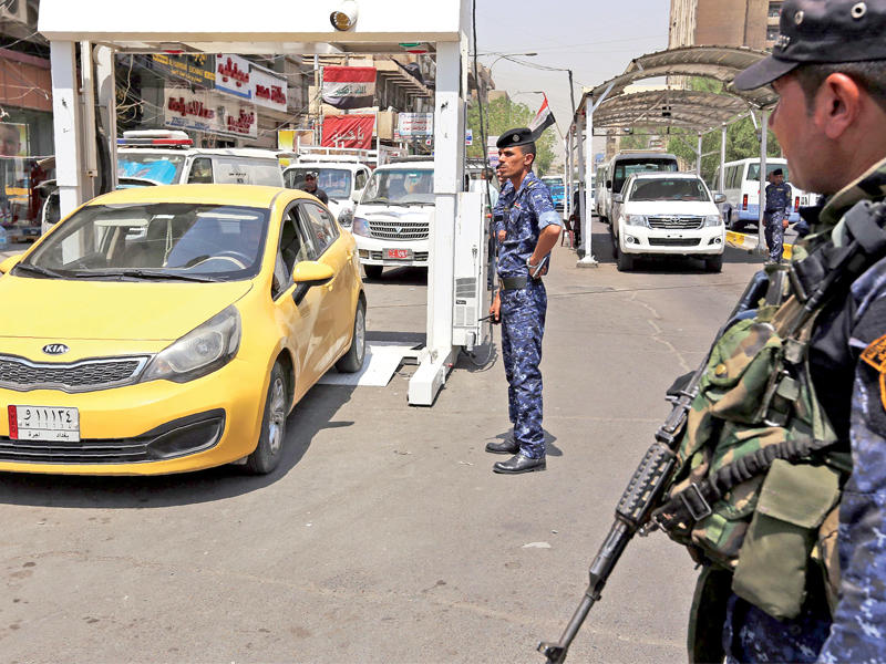 شرطي عراقي يفحص سيارة بجهاز جديد للكشف عن المتفجرات في كرادة وسط بغداد أمس (أ ف ب)