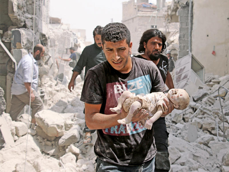 سوري يحمل رضيعاً قتل في قصف نظامي على حي باب النيرب بحلب أمس (أ ف ب)