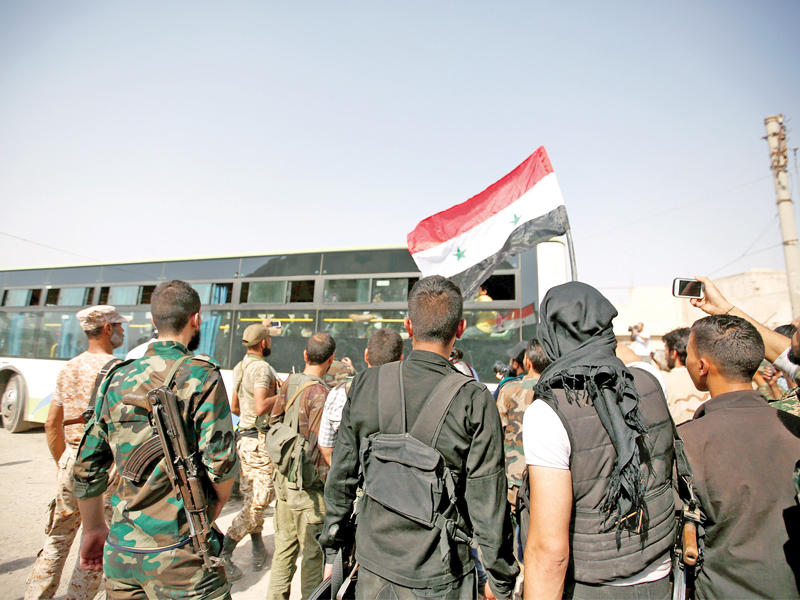 جنود النظام يتابعون إجلاء الدفعة الأولى من سكان داريا أمس (رويترز)