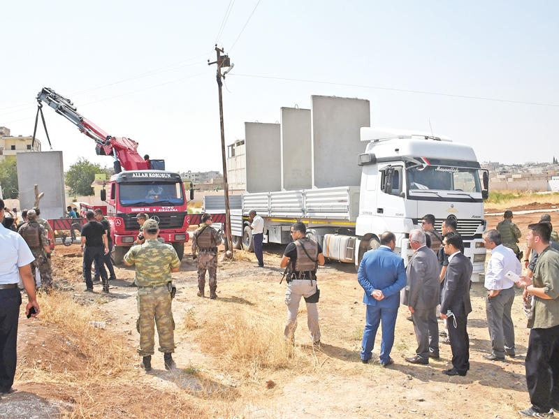  مسؤولون أتراك يتفقدون بناء جدار على الحدود بين مدينة سروج وكوباني الكردية السورية أمس الأول   (رويترز)