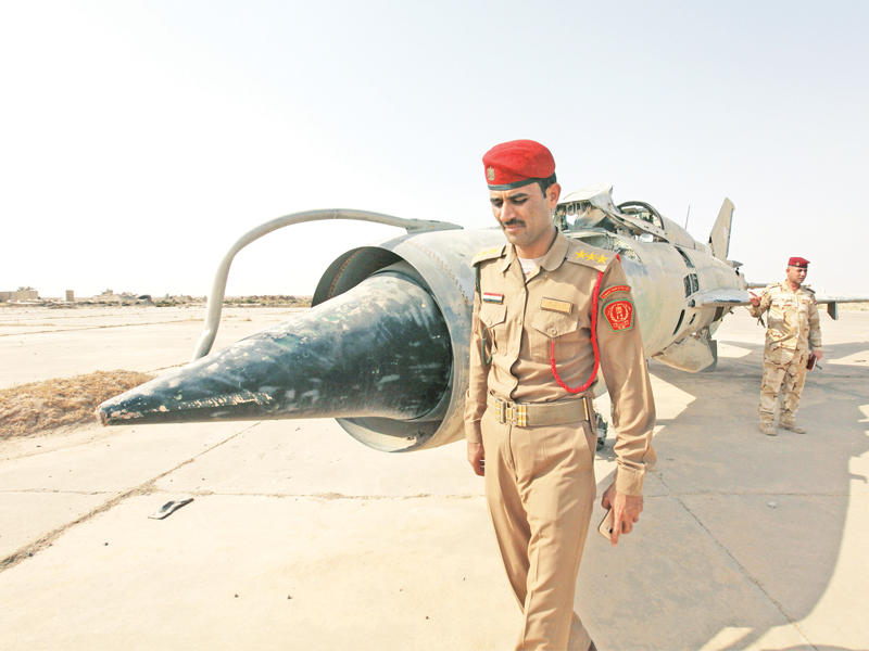 طياران عراقيان بجانب طائرتهما العسكرية في قاعدة القيارة أمس (رويترز)