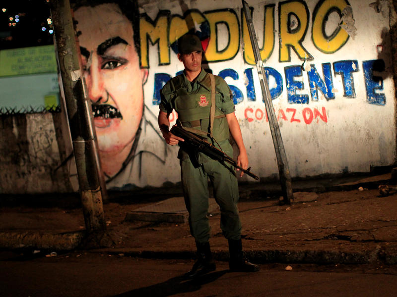 جندي يقف أمام صورة لمادورو على جدار في كراكاس