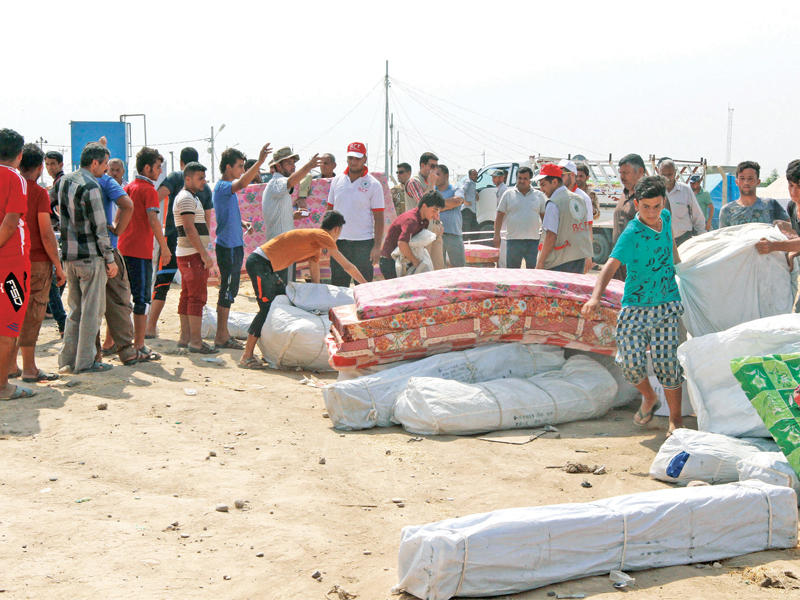 عراقيون ينتظرون توزيع مواد الإغاثة قرب كركوك أمسt(رويترز)