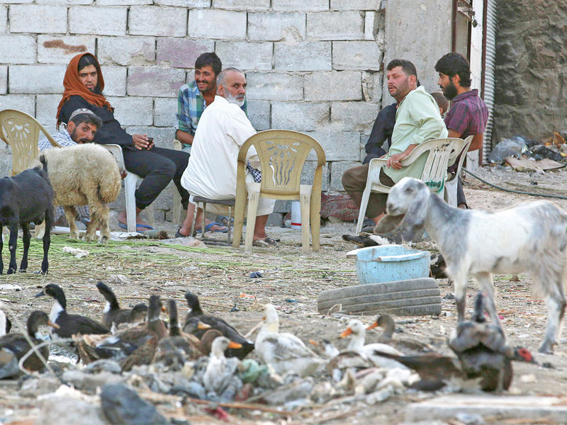 عائلة سورية تتقاسم الجلوس مع ممتلكاتها في حظيرة بحي الشيخ في حلب أمس الأول  (أ ف ب)