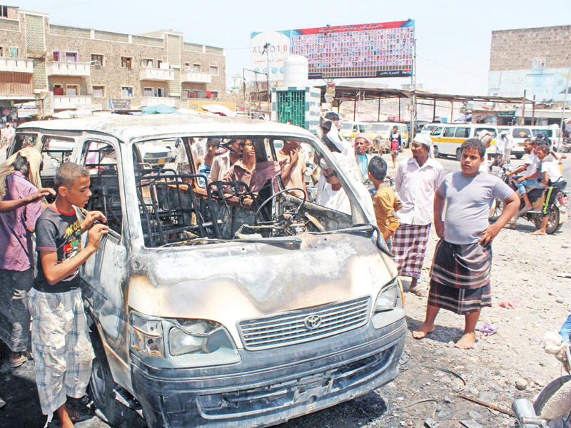 يمنيون يتجمعون حول سيارة احترقت بانفجار لغم حاولت القوات الحكومية تفكيكه في لحج أمس                  (أ ف ب)