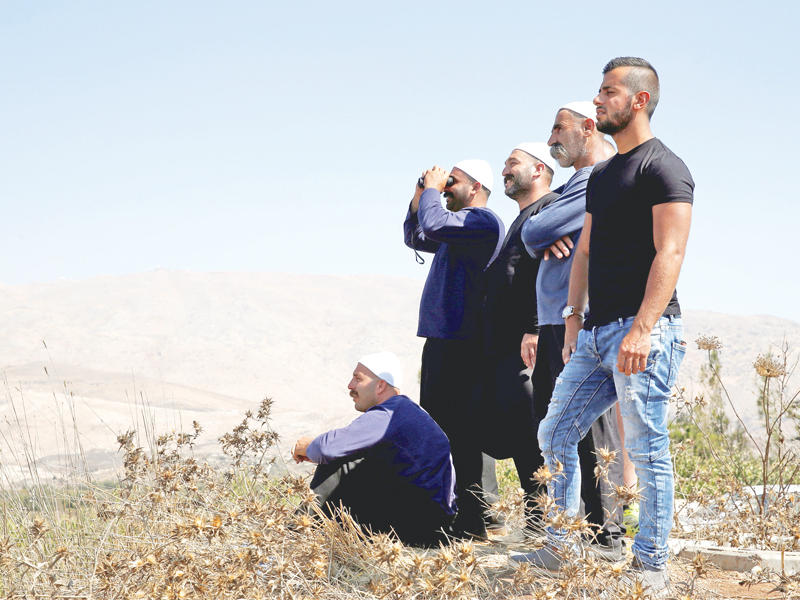 دروز يتابعون العمليات في سورية من الجولان المحتل أمس  (رويترز)