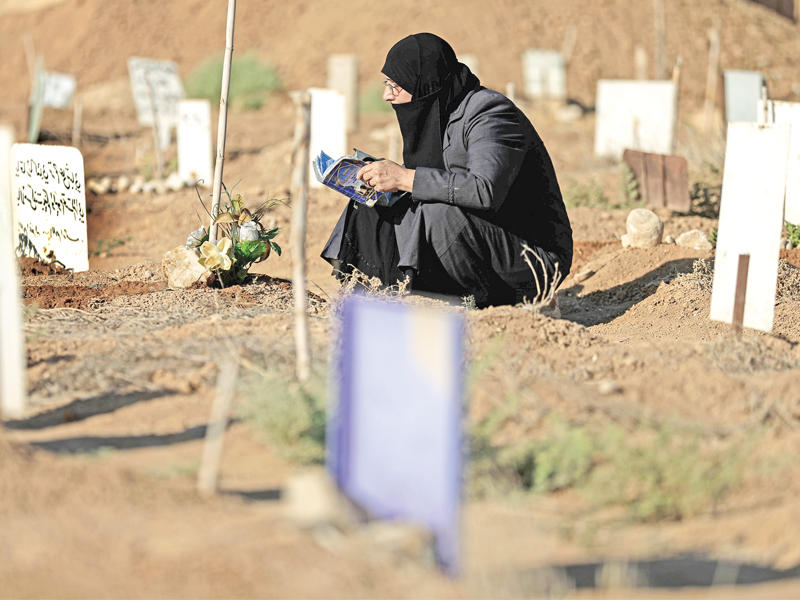 سورية تتلو القرآن الكريم على روح نجلها في مقبرة دوما أمسt(أ ف ب)