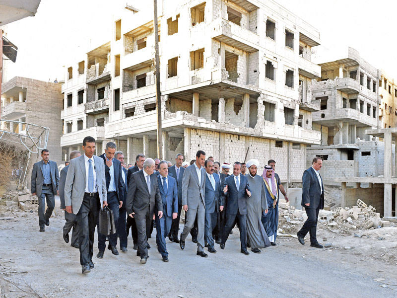 الأسد يتجول مع مسؤولي نظامه في أحد شوارع داريا المدمرة بعد صلاة العيد أمس (أ ف ب)