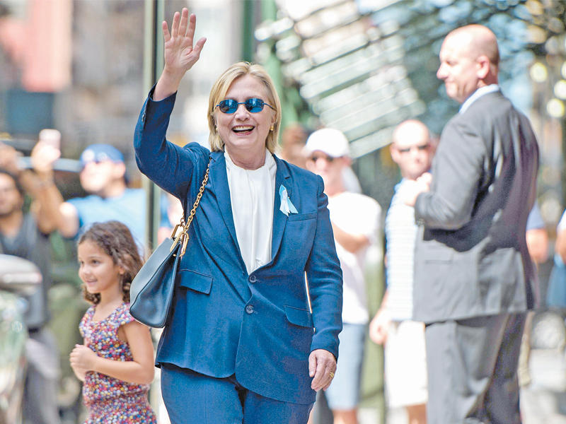 كلينتون تحيي الصحافيين بعد استراحة بمنزل ابنتها في نيويورك الأحد (أ ف ب)