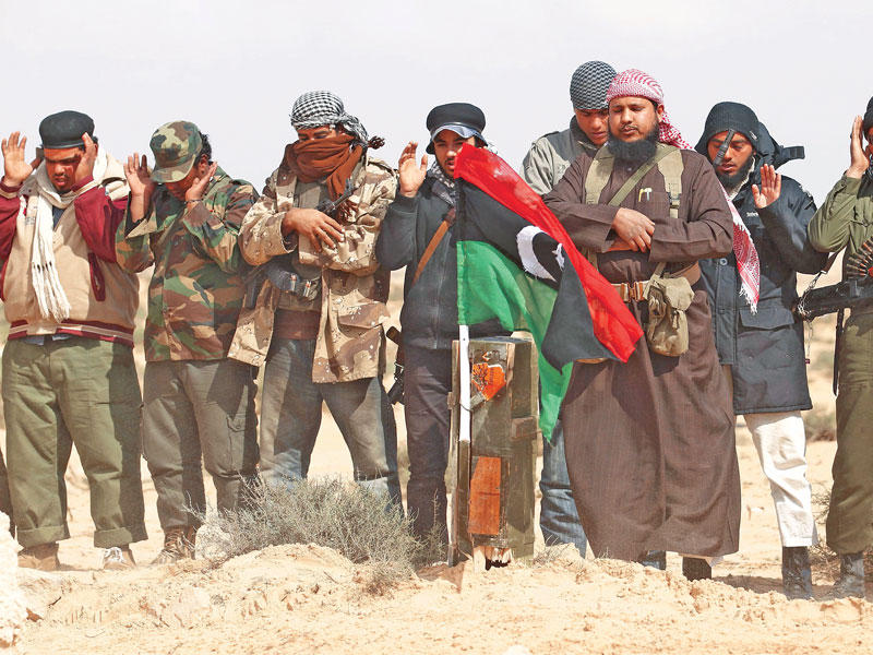 مقاتلون ليبيون يؤدون صلاة الجنازة على زملاء لهم قتلوا في غارة جوية لقوات التحالف التي تدخلت للإطاحة بالقذافي مطلع 2011 (رويترز)