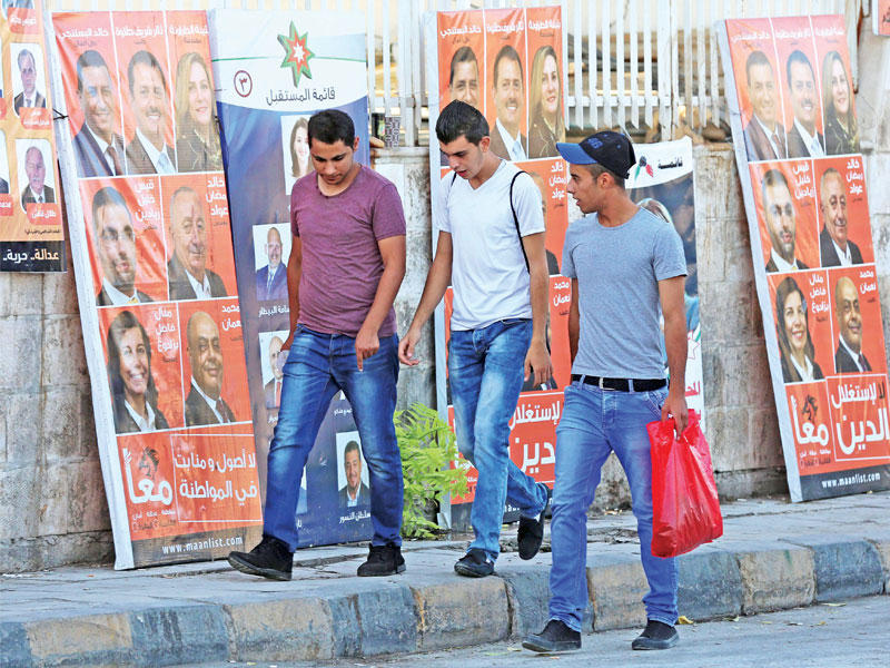 أردنيون يمرون بجوار ملصقات دعائية في عمان الأربعاء الماضي   (إي بي أيه)