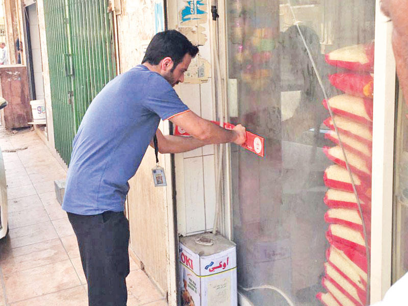 موظف بلدي خلال إغلاق أحد المحلات المخالفة