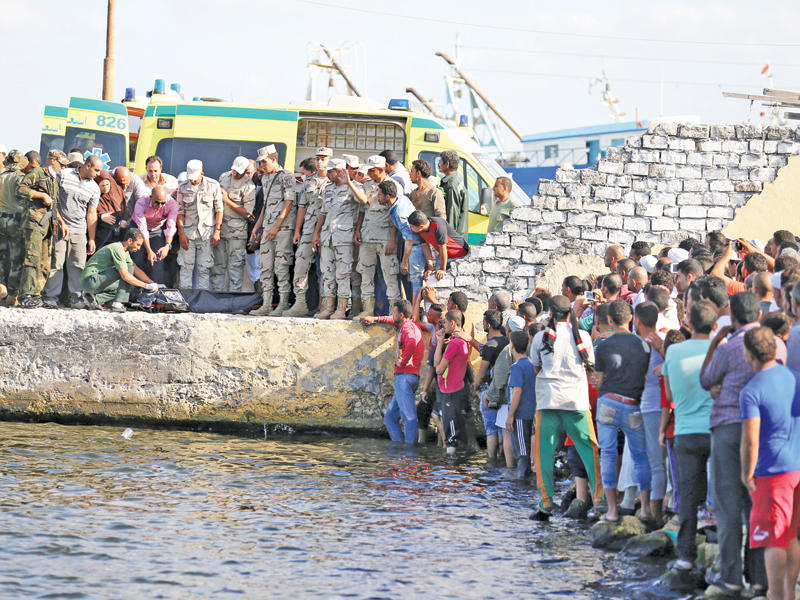 أفراد من الجيش وأهالي ينتشلون جثة لأحد ضحايا مركب الهجرة بمدينة رشيد المطلة على البحر المتوسط أمس (رويترز)