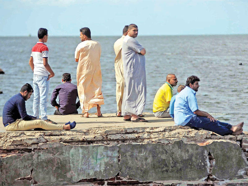 مصريون يتابعون عمليات انتشال الجثث مقابل مدينة رشيد أمس الأول (أ ف ب)