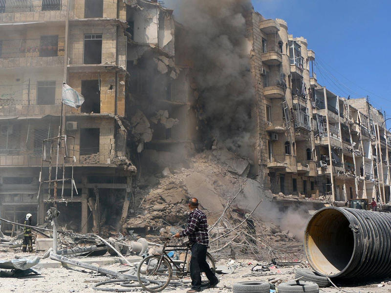 رجل يتابع جهود اطفاء النيران في أحد الأبنية التي طال القصف محيطها واحدث العديد من الخسائر بها