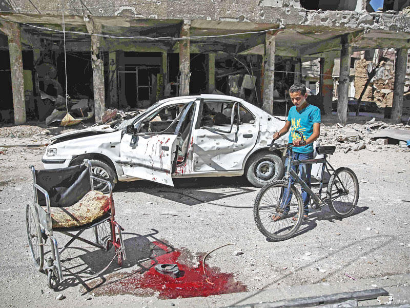 صبي سوري أمام موقع قتل فيه معاق على كرسيه المتحرك في دوما أمس (أ ف ب)