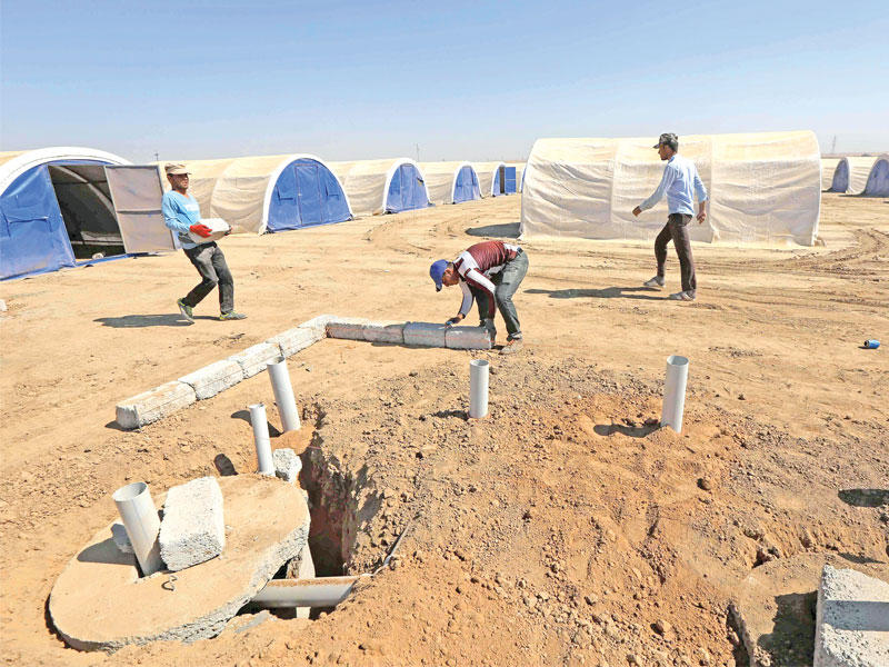 عمال يجهزون خيماً للنازحين من مدينة الموصل في قرية حسان شام أمس الأول (أ ف ب)