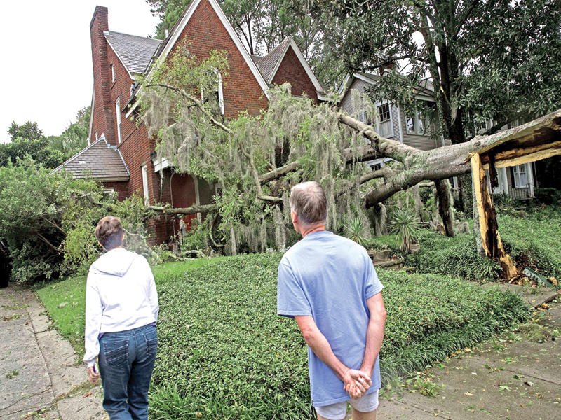 أميركيان يتفقدان منزلاً دمرته شجرة في سافانا بجورجيا أمس الأولn(أ ف ب)