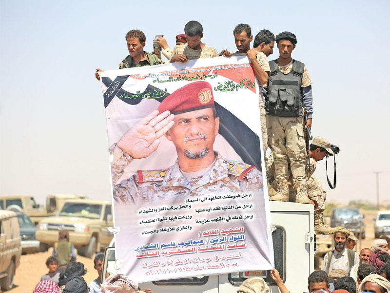 مقاتلون مع السلطات الشرعية يحملون صورة الشدادي خلال تشييعه في مأرب أمس   (رويترز)