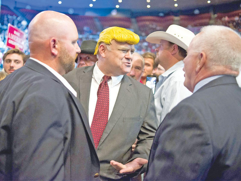 مؤيد لترامب يرتدي زياً تنكرياً أثناء اقتياد عناصر الأمن له للخارج في ولاية أوهايو أمس الأول (أ ف ب)