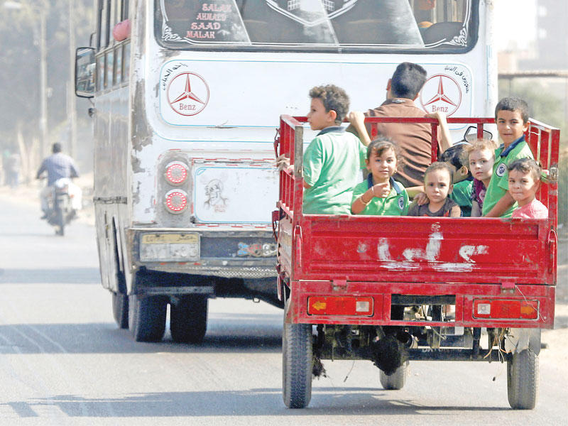 أطفال مصريون يتوجهون إلى مدرستهم على متن مقطورة أمس الأول على طريق زراعي يؤدي إلى القاهرة أمس (رويترز)