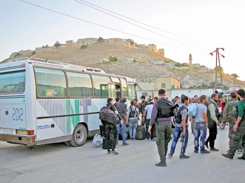 طلائع المقاتلين السوريين وأسرهم الذين خرجوا بأسلحتهم من قدسيا والهامة في ريف دمشق باتفاق مع النظام يصلون إلى محافظة إدلب أمسt(أ ف ب)