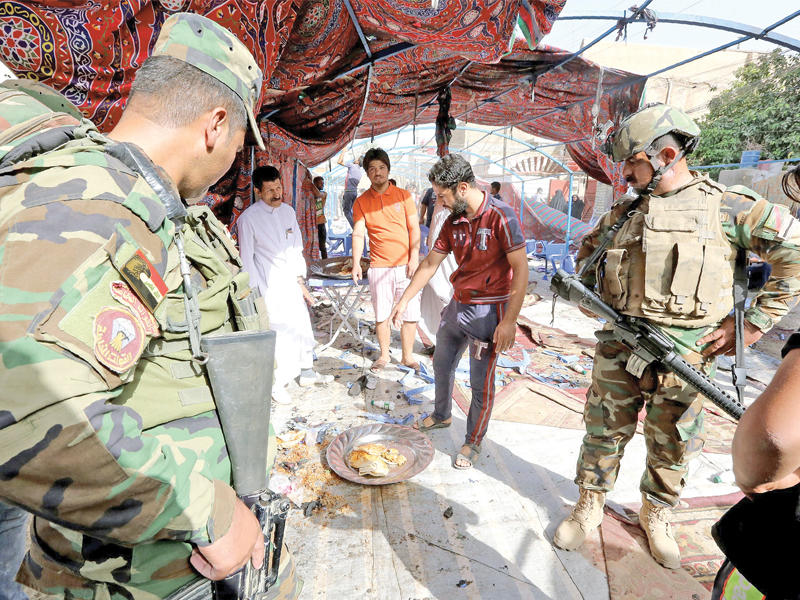 مواطنون وشرطيون عراقيون يتفقدون مكان التفجير بمجلس العزاء في بغداد أمس (أ ف ب)