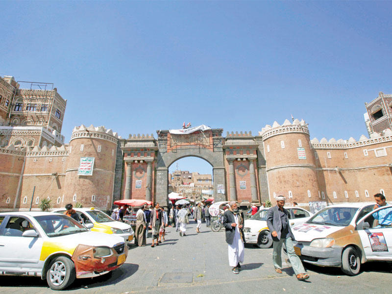 يمنيون أمام بوابة صنعاء القديمة أمس    (رويترز)