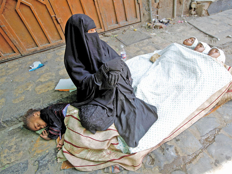 يمنية تفترش الطريق مع أولادها طلباً للمساعدة في السوق القديم بصنعاء أمس               (رويترز)