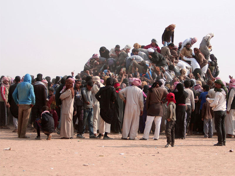 نازحون عراقيون وسوريون يشترون الطعام والماء في منطقة يسيطر عليها الأكراد بمحافظة الحسكة السورية على الحدود مع العراق أمس (رويترز)