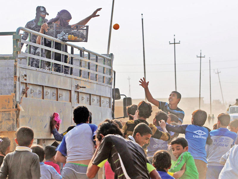 جنديان عراقيان يوزعان الفواكه على أطفال قرية الخوين جنوب الموصل بعد طرد «داعش» منها أمس الأول (أ ف ب)
