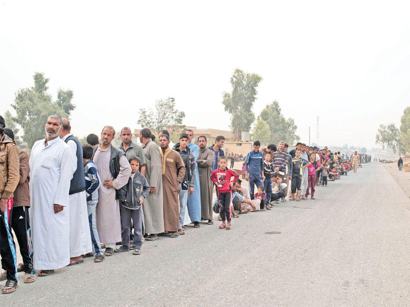 نازحون عراقيون ينتظرون دورهم للحصول على مساعدات أممية أمس في قرية إبراهيم الخليل بقضاء الحمدانية على بعد كليومترات قليلة من الموصل  (رويترز)