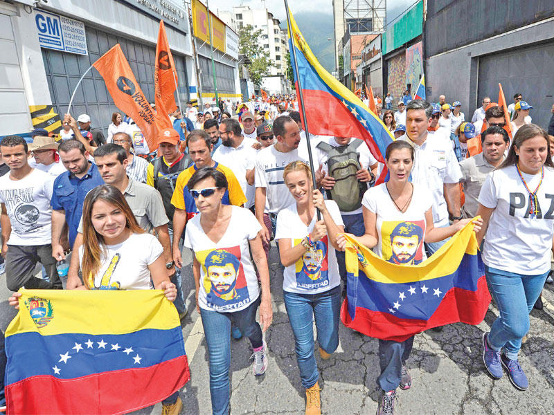 معارضون فنزويليون تتوسطهم زوجة المعارض المسجون ليوبولدو لوبيز خلال تظاهرة في كراكاس أمس (أ ف ب)