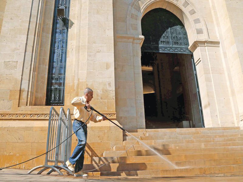 رجل ينظف درج مبنى مجلس النواب بوسط بيروت أمس ( رويترز)