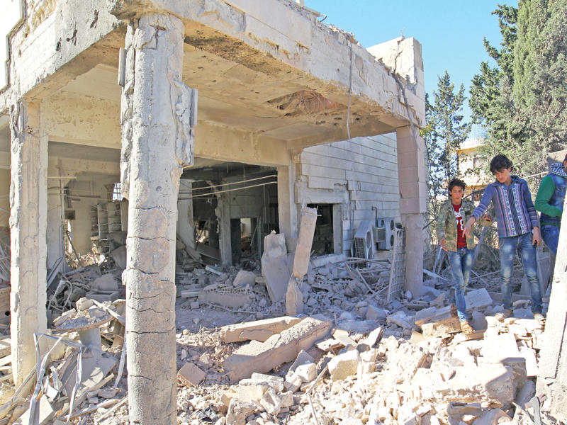 فتية يتفقدون مبنى دمرته غارة نظامية على بلدة أورم الكبرى بحلب أمس الأول  (رويترز)