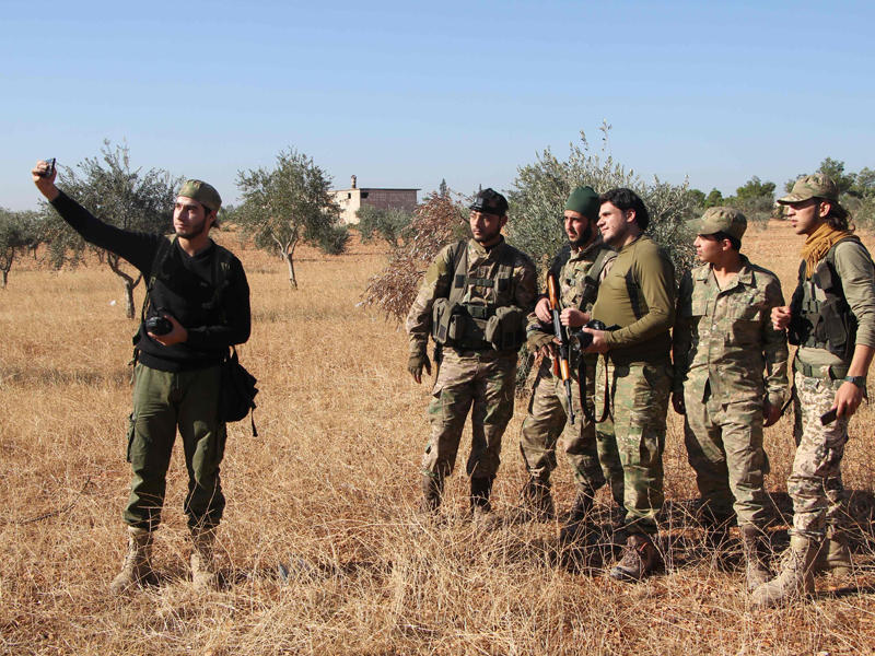 مقاتلون في جيش الفتح يلتقطون سيلفي على مدخل ضاحية الأسد بحلب الغربية أمس الأول (أ ف ب)