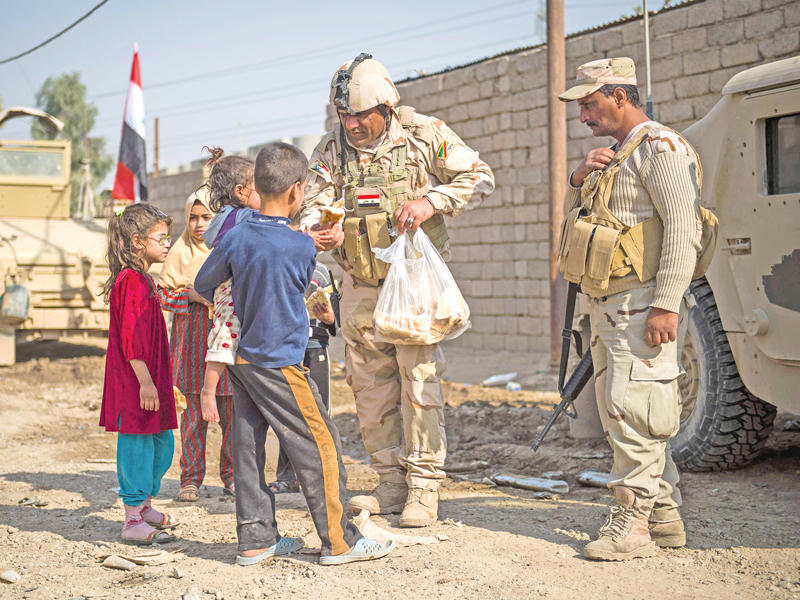 جنديان عراقيان يوزعان الخبز على أطفال في حي الانتصار شرق الموصل أمس (أ ف ب)