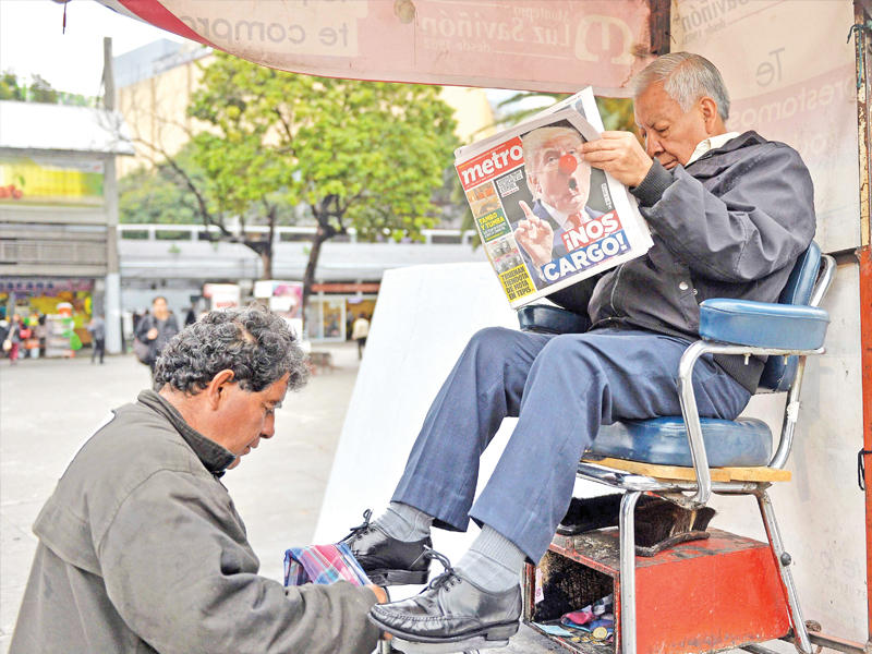 مكسيكي يطالع أخبار فوز ترامب على كرسي ملمع أحذية في مكسيكو سيتي أمس      (أ ف ب)