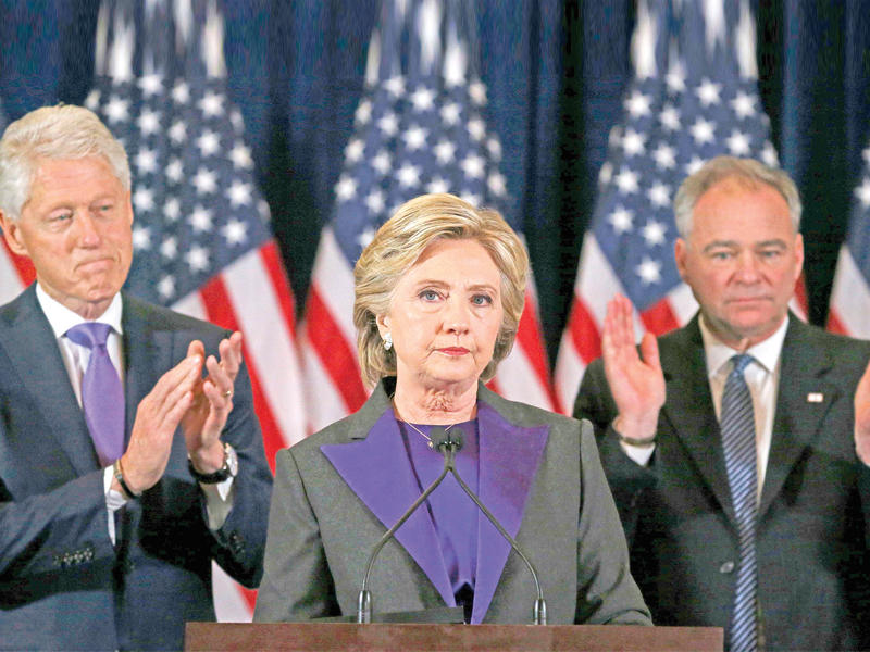كلينتون تتوسط زوجها الرئيس السابق بيل كلينتون والسيناتور تيم كاين الذي خاض معها المعركة الرئاسية خلال خطاب الهزيمة في نيويورك أمس (رويترز)