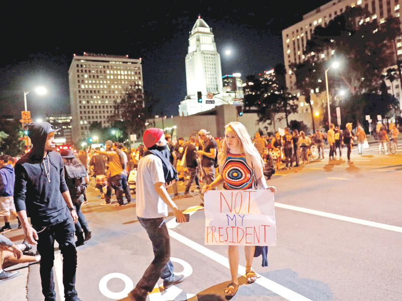 شابة اميركية تحمل لافتة كتب عليها «ليس رئيسي» في لوس انجلس بكاليفورنيا أمس  (رويترز)