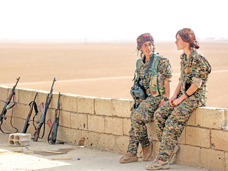 مقاتلتان كرديتان في استراحة على سطح منزل بقرية مزرعة خالد بريف الرقة أمس الأولt(أ ف ب)