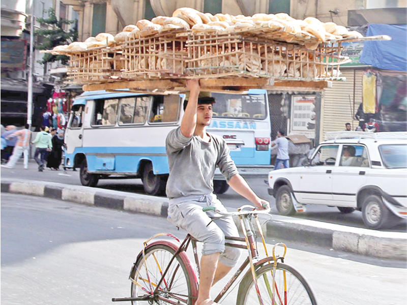 بائع خبز مصري يجول على دراجته في أحد احياء القاهرة أمس  (إي بي أيه)