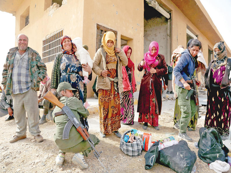 شرطي كردي يفتش سوريات فررن من الرقة إلى عين عيسى أمس الأول (أ ف ب)