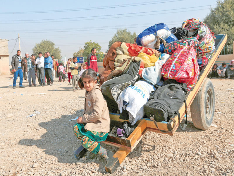 طفلة عراقية تحرس أمتعة عائلتها الفارة من الموصل أمس (رويترز)n