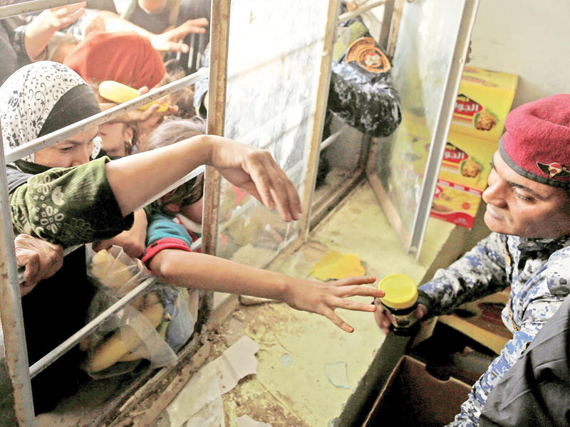 عراقيون يصطفون للحصول على مساعدات غذائية في إحدى مدارس حمام العليل جنوب الموصل أمس  (رويترز)