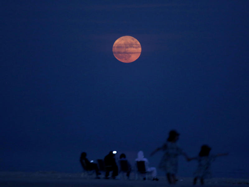 عائلة كويتية تراقب ظاهرة القمر العملاق الفلكية النادرة على شاطئ البحر (ا ف ب)