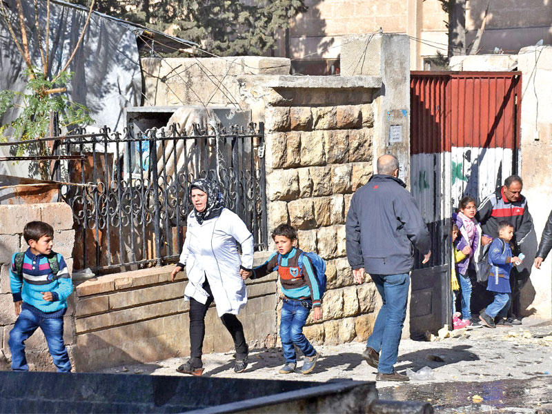 سوريون يصطحبون أبناءهم من المدرسة التي قتل فيها 7 تلامذة في حلب الغربية أمس (أ ف ب)